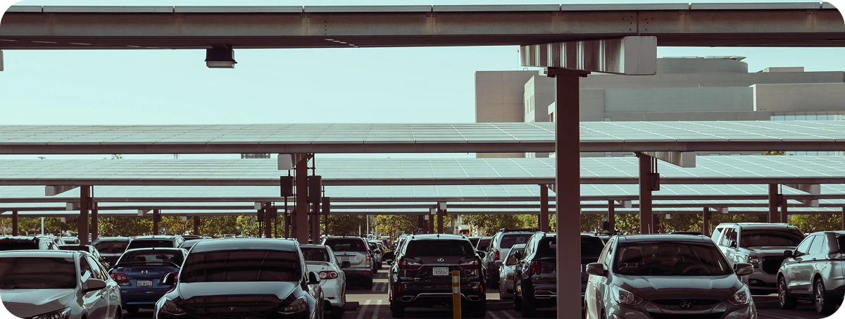 Ombrières photovoltaïques, distribuées par rangée sur un large parking. Véhicules stationnés sous les ombrières photovoltaïques, à l'abri du soleil et des intempéries.